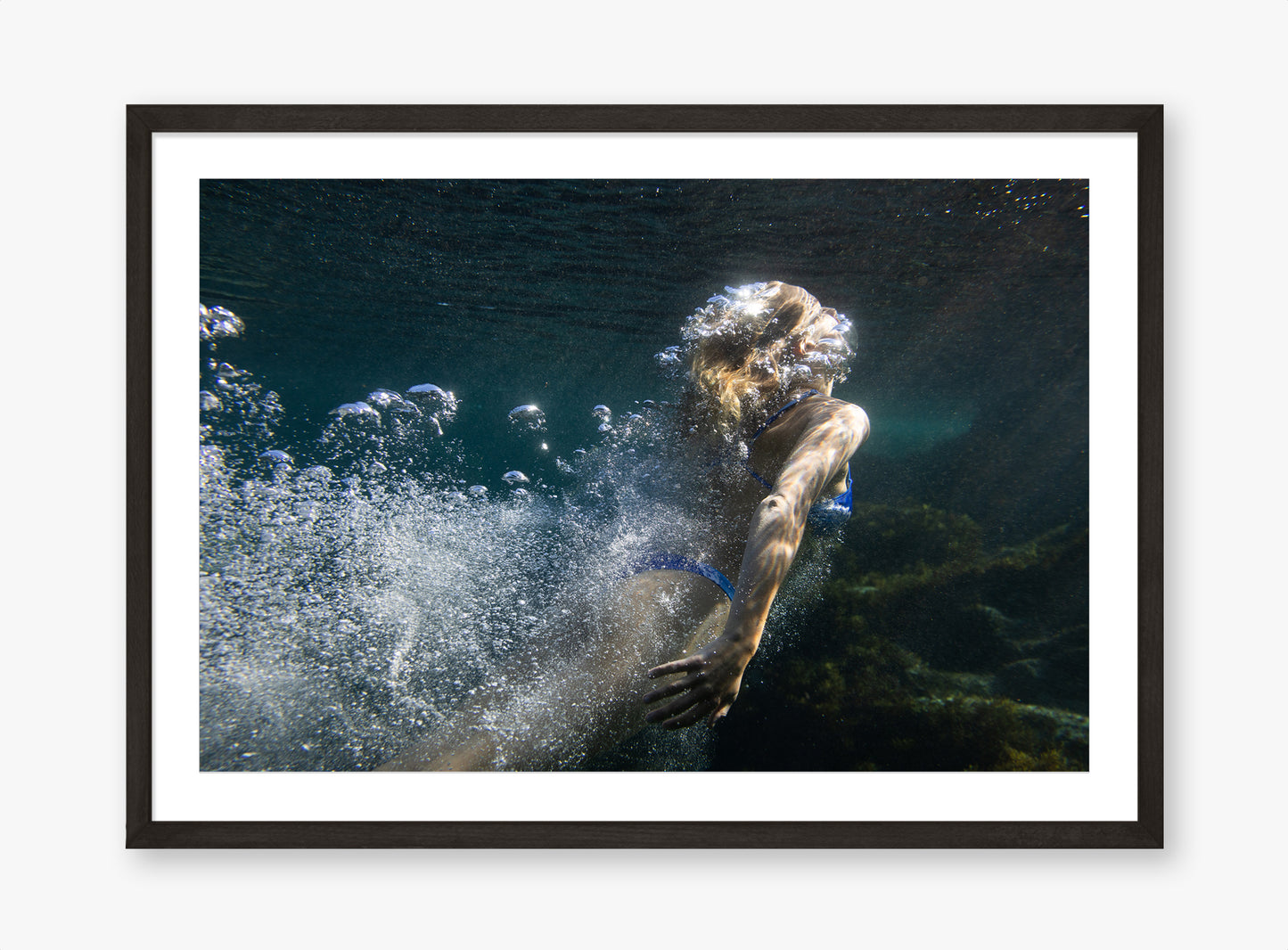 Framed underwater photograph of a person swimming with bubbles