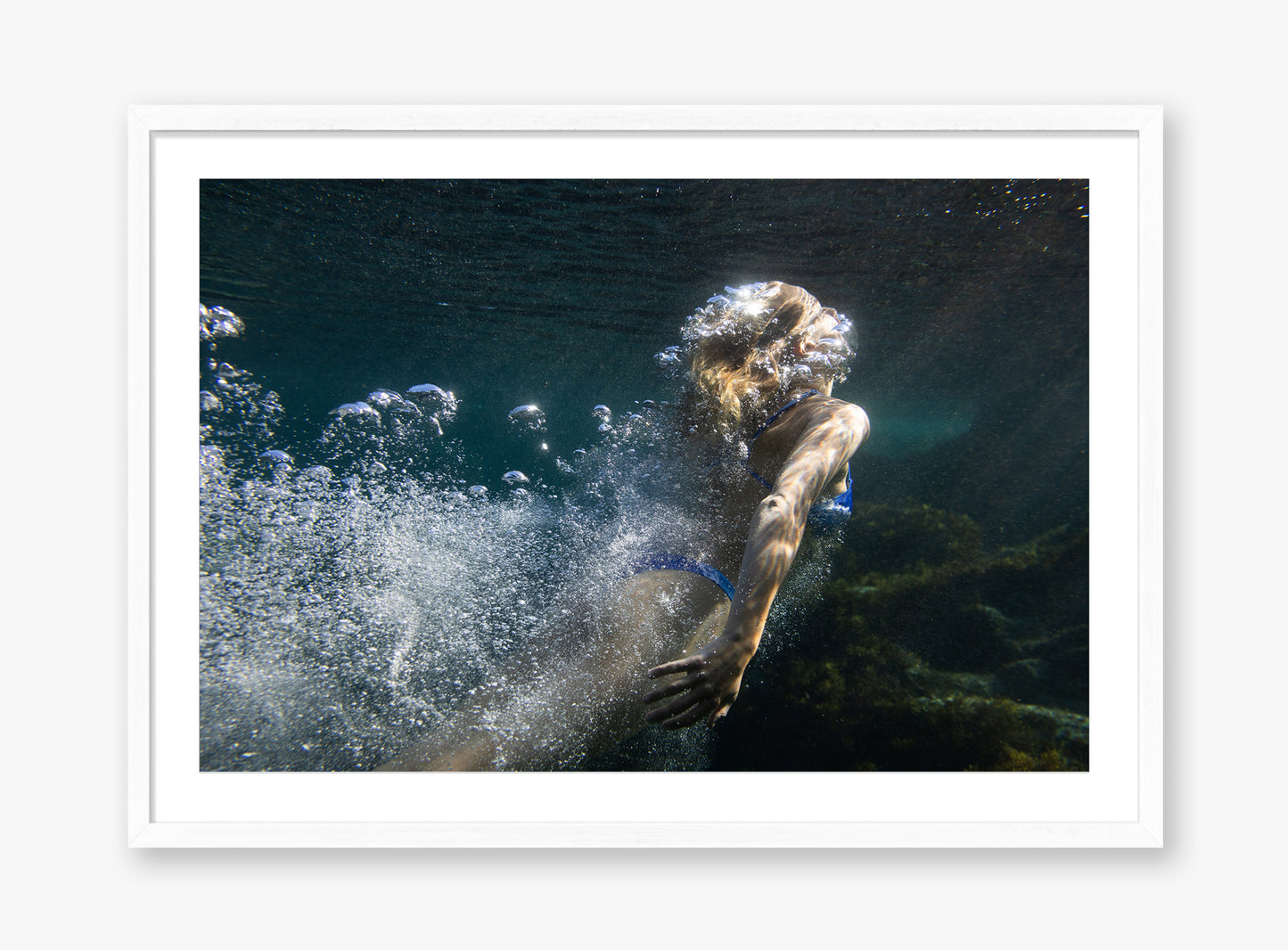 Person swimming underwater with bubbles and a white frame